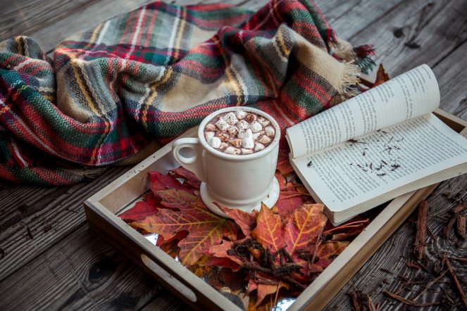 A mug of hot chocolate next to an open book